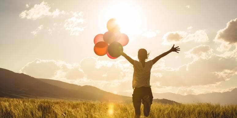 30 Best Songs About Hope When You Need A Little Inspiration hopeful woman holding balloons while watching the sun