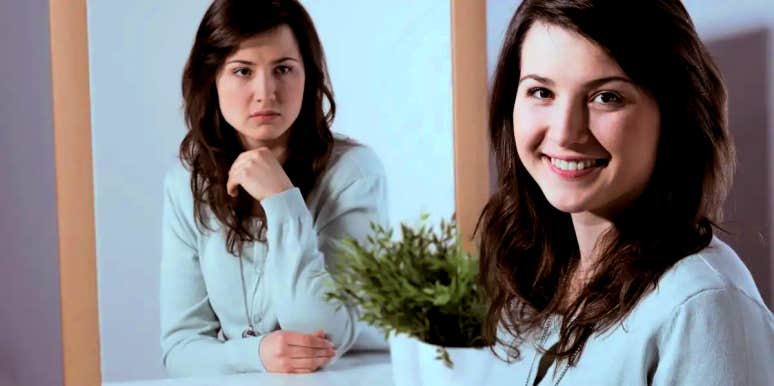 8 Signs Of An Emotionally Unstable Woman To Watch Out For woman smiling at the camera while her mirror image gives her a mean look