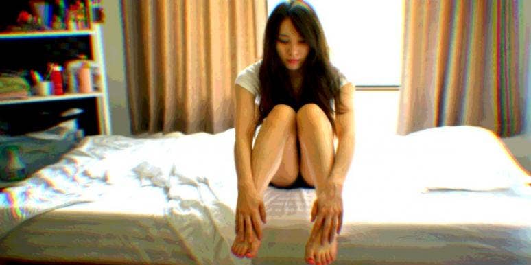 9 Signs & Symptoms Your IUD Moved Out Of Place sad woman sitting on a bed worried her IUD moved out of place