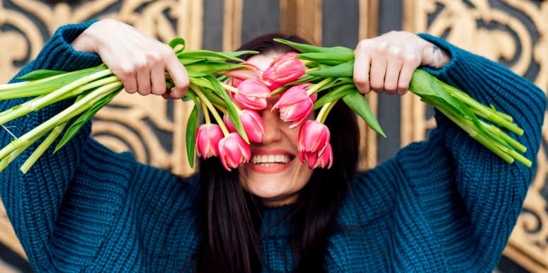attractive woman hiding part of her face behind flowers