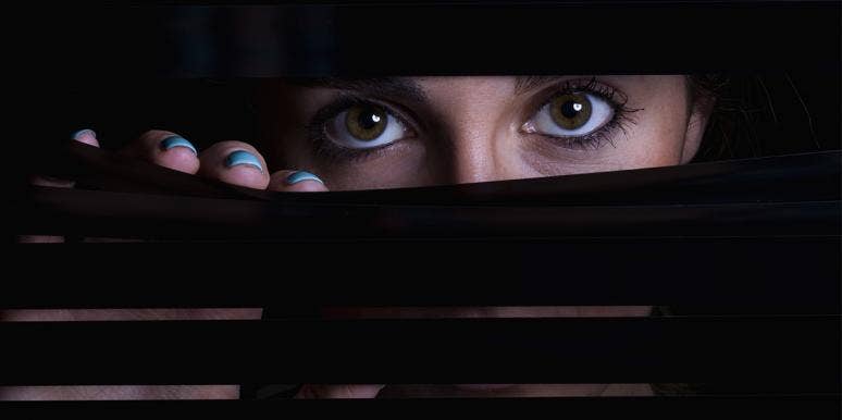 woman peeking from behind blinders
