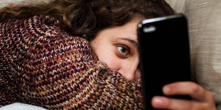 woman in sweater scrolling phone