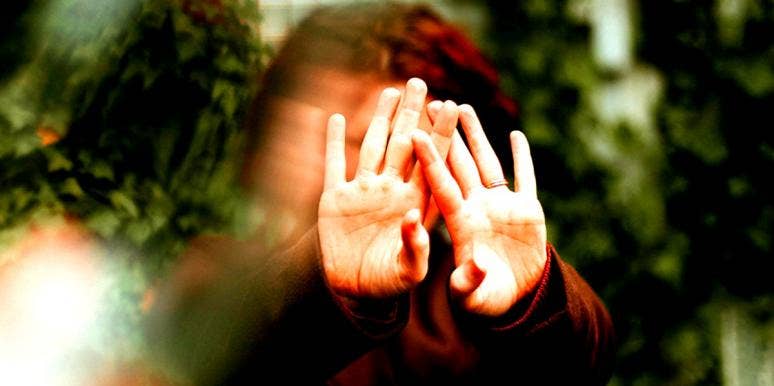 My Child Was Diagnosed With Schizophrenia, Here's How I Coped person covers their face with their hands with a blurred background