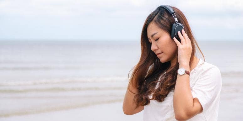 100 Songs About Loneliness, Isolation & Feeling Lonely woman listening to music on beach