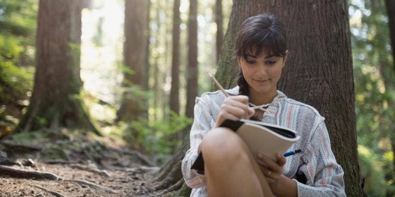 woman writing in notebook in the forest