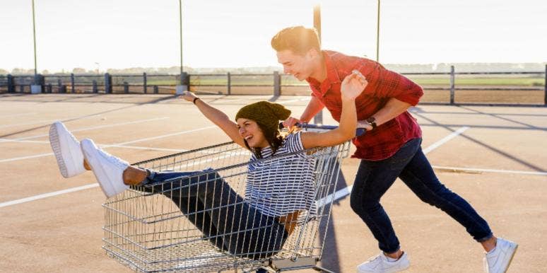 man pushing woman in shopping cart
