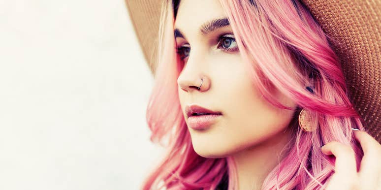 young woman with pink hair and hat, looking away