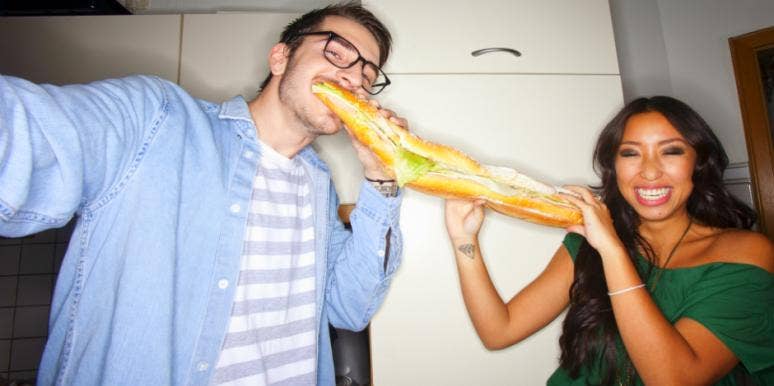 7 Real Hangry Symptoms You Feel When You’re Hungry & Why man and woman sharing a sub sandwich