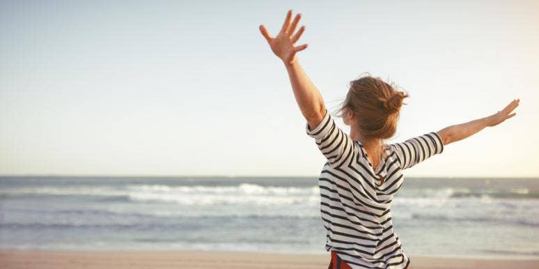 woman on beach with arms outstretched