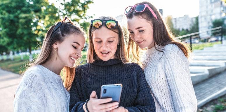 teens making friends three teenage girls looking at a smartphone
