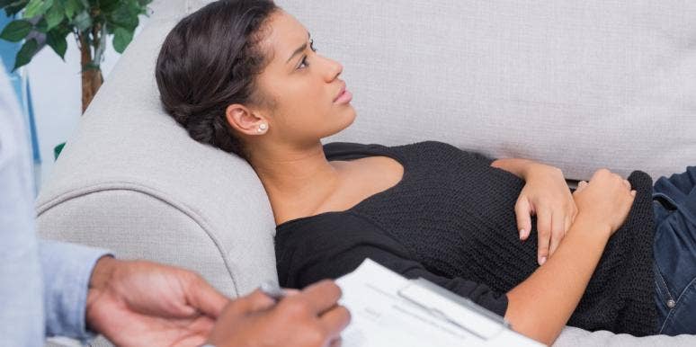 Black woman laying on couch in therapist's office while therapist takes notes