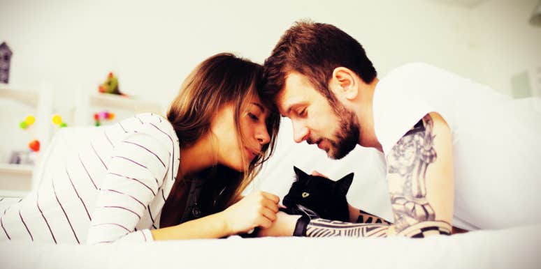 what you should never do as a partner, advice from a trauma therapist couple in a white bed snuggling their black cat