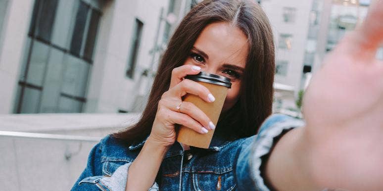 How Much Caffeine Is Too Much For Your Body? woman holding a cup of coffee hiding her face