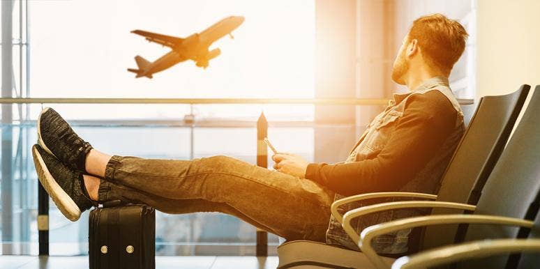 7 Ways Traveling Actually Makes You Healthier, Says Science man in airport looking at plane