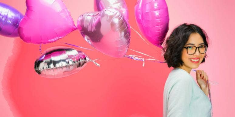 10 Valentine’s Day Traditions From Around The World woman smiling holding heart balloons