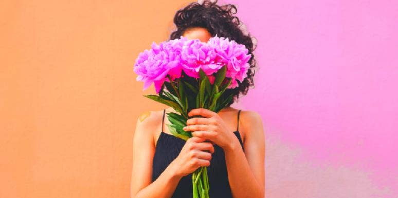 What To Get A Woman for Valentine’s Day, By Zodiac Sign woman holding flowers in front of face