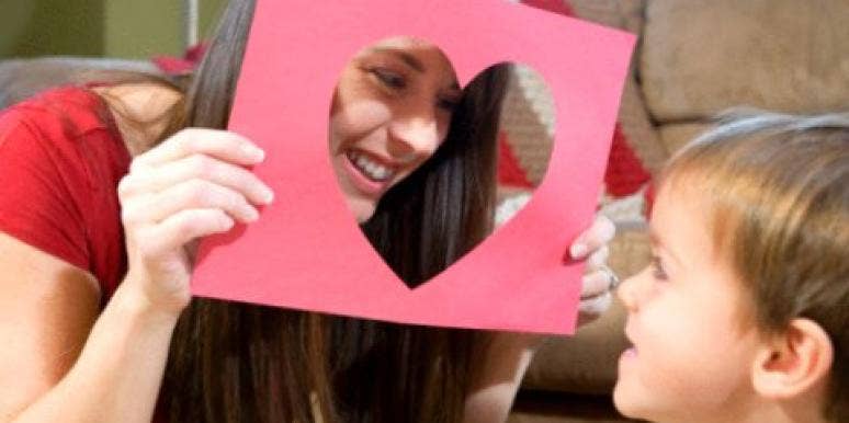 Peekaboo! young woman peeking throught heart-shaped cutout at little boy