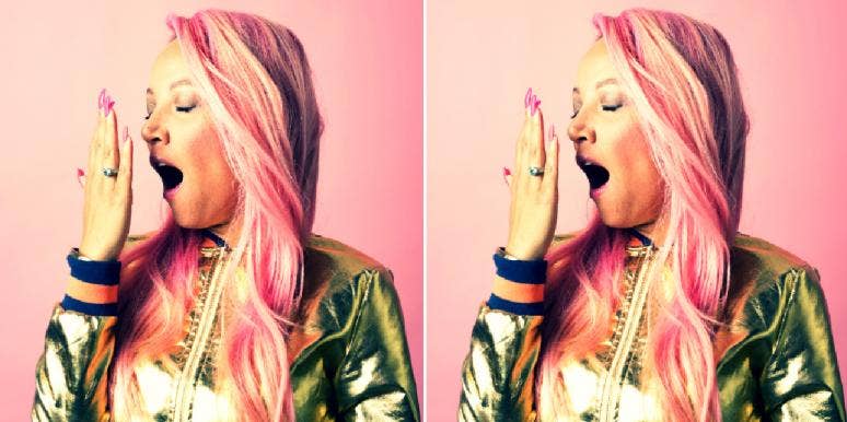 woman with pink hair and nails yawning