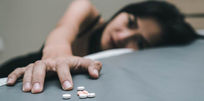 woman laying on table next to pills