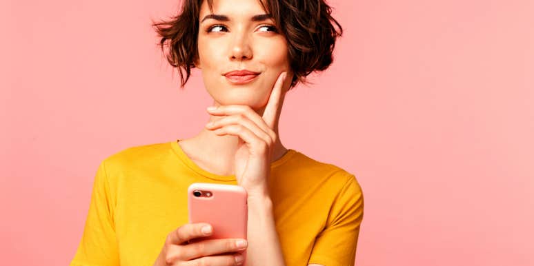 What To Message Guys On Tinder To Start A Fun Conversation woman holding cellphone wondering what to say to a guy on Tinder