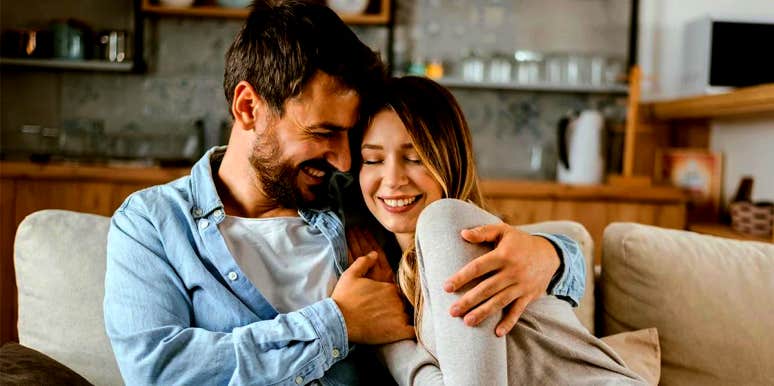 What Wives Need From Their Husbands husband and wife sitting on couch hugging and smiling