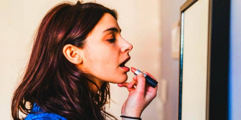 7 Relationship Mistakes Men Make That Cause Women To Feel Unloved woman putting lipstick on in the mirror