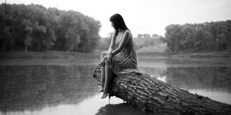 woman sitting alone on log