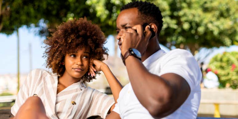 13 Reasons Why Guys Act Distant When They Like You woman looking at guy acting distant talking on the phone