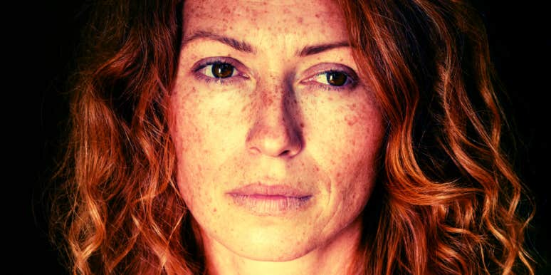 redheaded woman with freckles staring into space with sad eyes