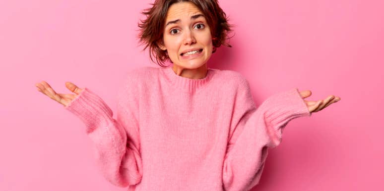 young woman in pink sweater shrugging her shoulders