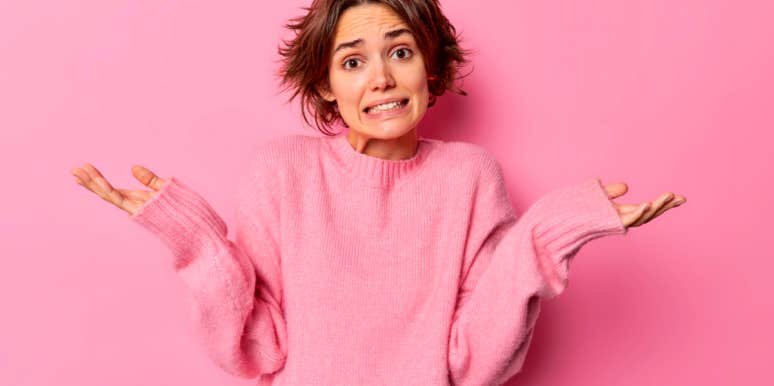 Why The Friend Zone Is Offensive (And Doesn't Exist) young woman in pink sweater shrugging her shoulders