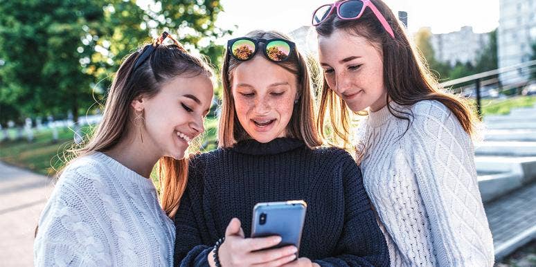 group of girlfriends looking at phone group of girlfriends looking at phone