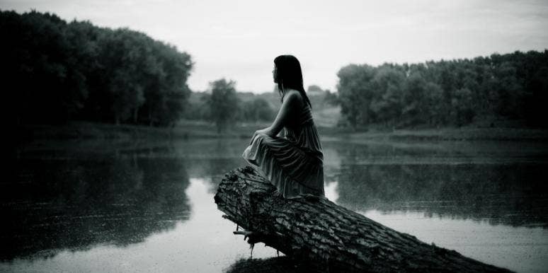 woman sitting on log over lake