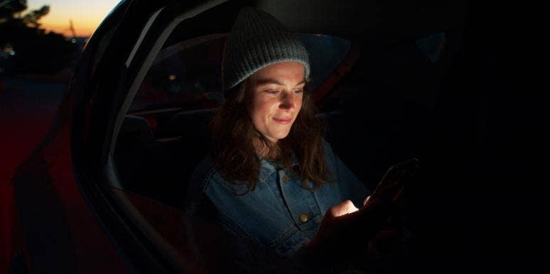 A woman is in the back of a car at night.