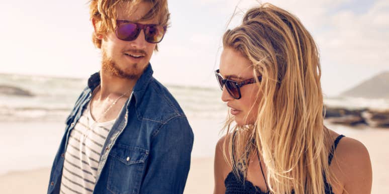 The mindset harming your dating life man and woman walking on the beach, she looks disinterested