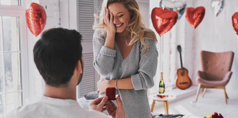 man holding engagement ring while making proposal to his happy girlfriend