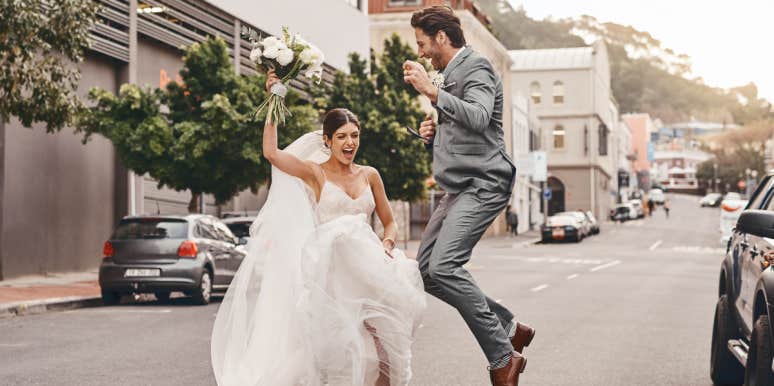 Bride and groom jumping in the street