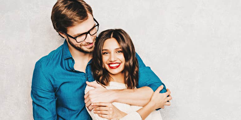 Women who find true love man and woman embrace, him behind her, against a concrete wall