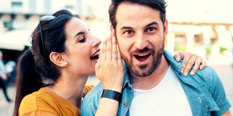 woman whispering words in man's ear to make him fall in love