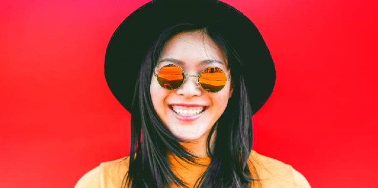 7 Warning Signs Someone Has A Superiority Complex woman wearing sunglasses and smiling with a red background