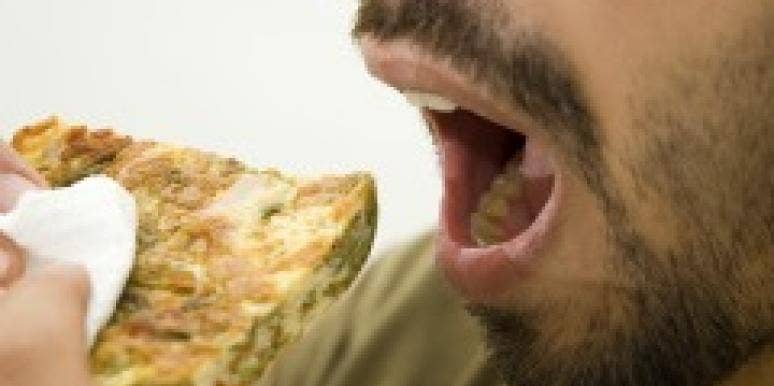Man's mouth eating a piece of bread