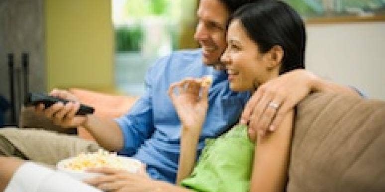 A man and woman watch TV.