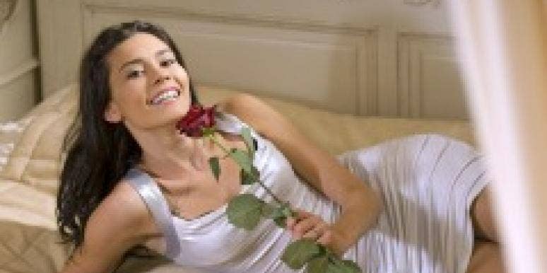 Woman with a rose lying on a bed