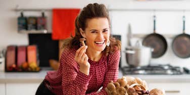 Happy young housewife with basket with mushrooms in kitchen