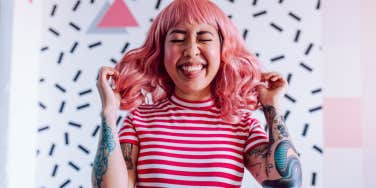 Woman with tattoos, pink hair and smile on her face