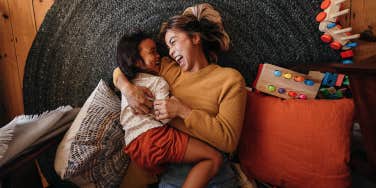 mom on floor laughing with young daughter