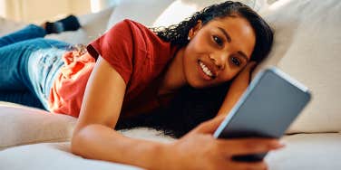 woman laying on couch texting