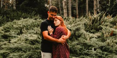 man hugging woman in forest