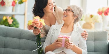 adult daughter and mother with gift box and flowers