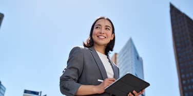 smiling business woman holding a tablet outside